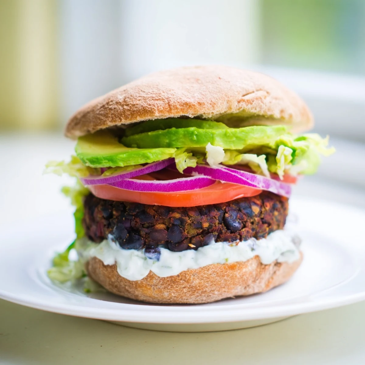 A close-up of a stacked Zesty Black Bean Burger with vibrant toppings, hinting at zesty flavors and textures.