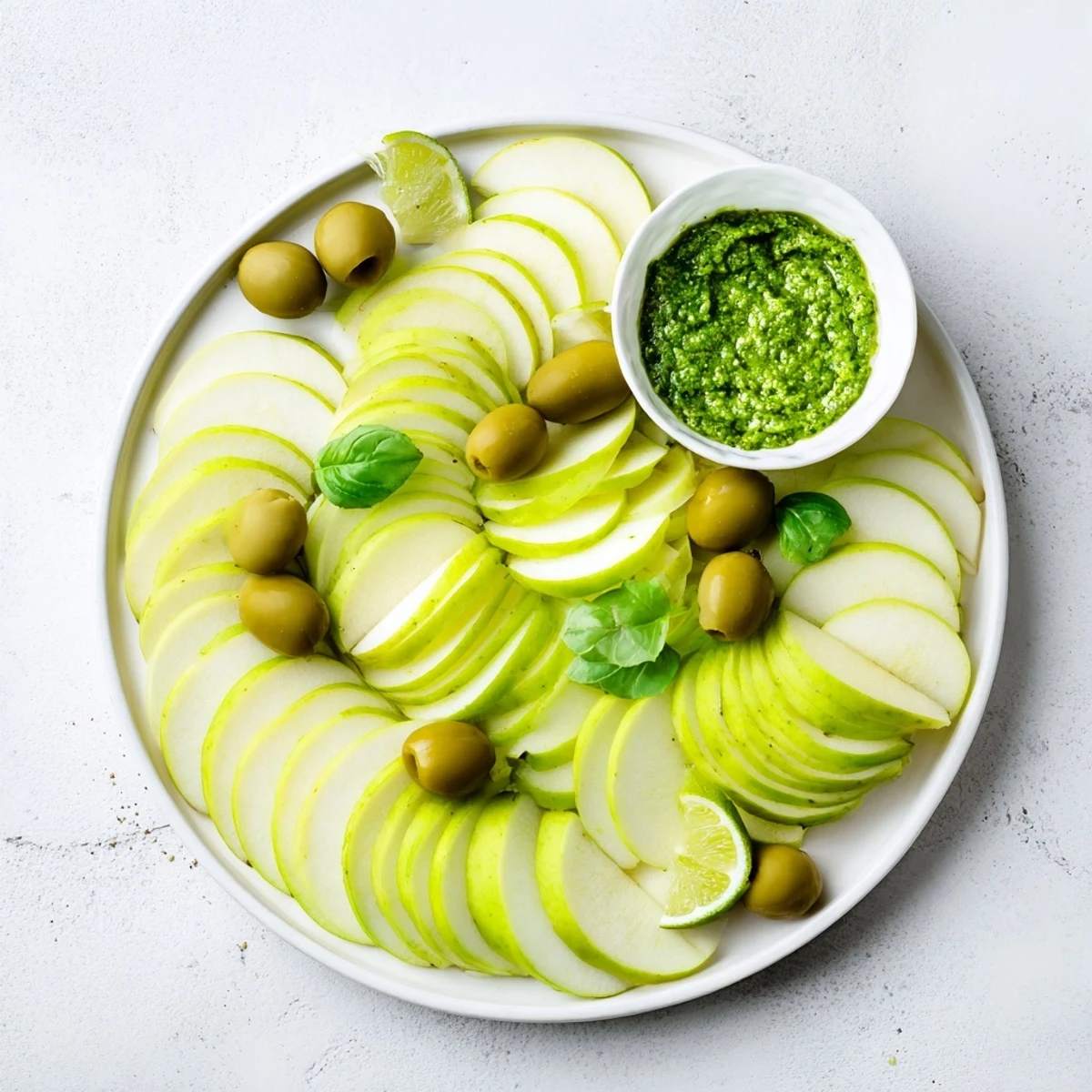A beautiful Emerald City snack board: bright green apples, olives, limes, and pesto for dipping.