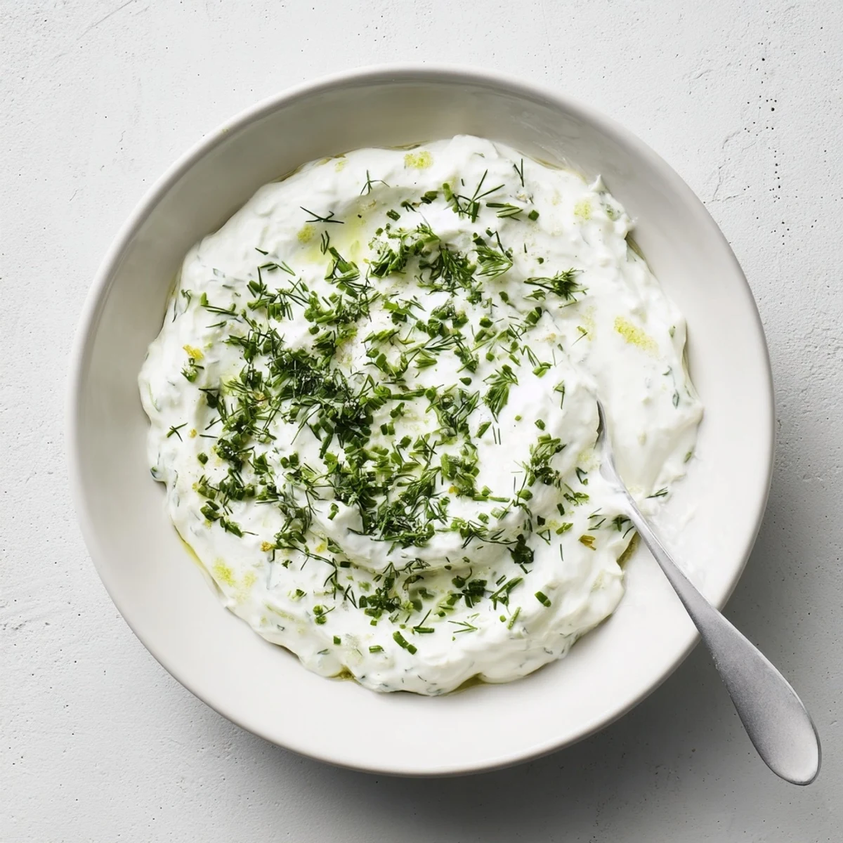 A chilled bowl of Greek Yogurt Herb Dip garnished with fresh dill and chives, served with colorful vegetable crudités.  