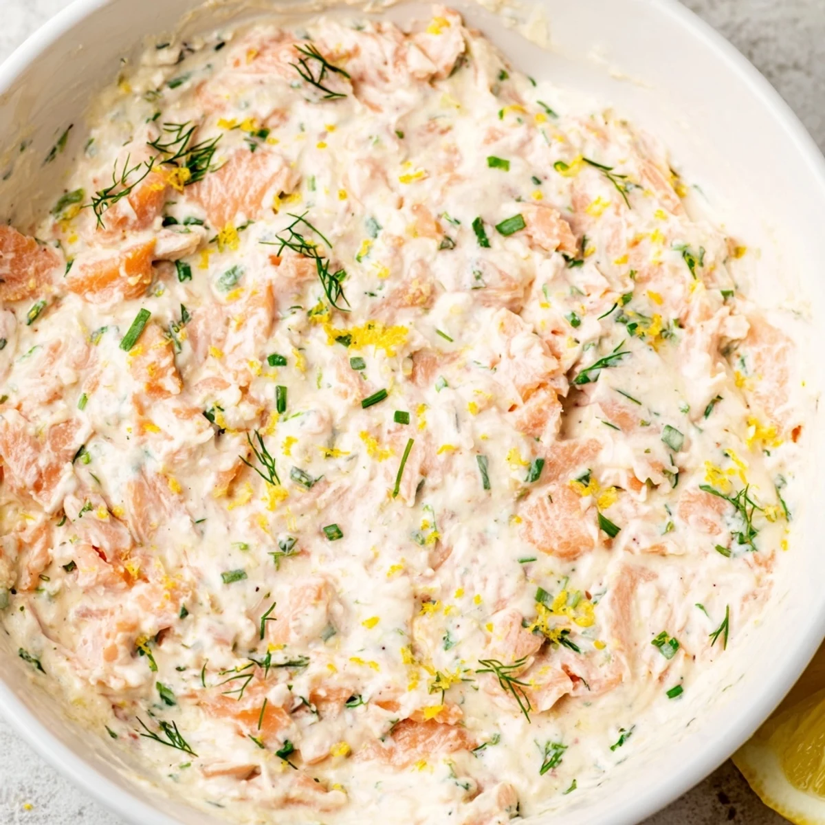 Rich and flavorful Smoked Salmon Dip in a serving bowl with chives, lemon wedges, and bagel chips for a delicious appetizer.