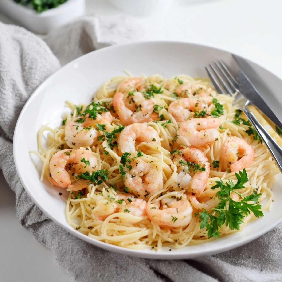 Tender angel hair pasta coated in a vibrant lemon-butter garlic sauce, with sautéed shrimp glistening and fresh parsley sprinkled on top.  