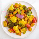 Colorful Anti-Inflammatory Turmeric Roasted Vegetables served warm over quinoa, garnished with fresh cilantro and a bright lemon drizzle.  