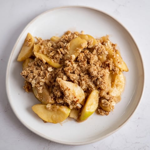 Warm Rustic Apple and Cinnamon Crumble bubbling with juicy apple filling and golden crumb topping.