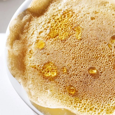 Golden, bubbly Moroccan Baghrir crepes are ready, drizzled with sweet, melted butter and honey.