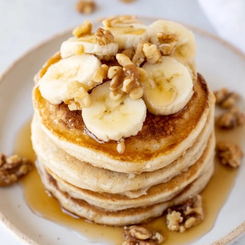 Fluffy weekend golden-brunch banana pancakes with sliced bananas and a generous drizzle of real maple syrup.