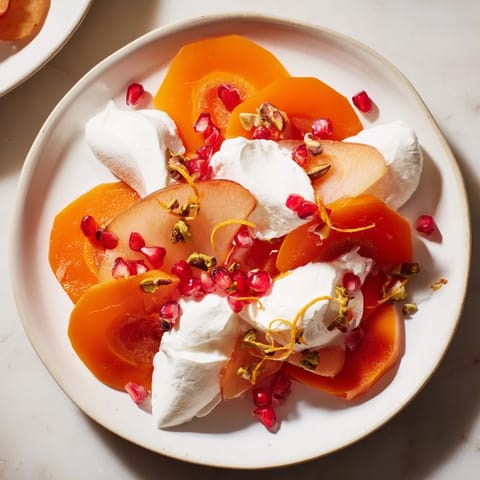 This persimmon and pear snowscape showcases sliced fruit draped in fluffy cream, ready to serve and enjoy.