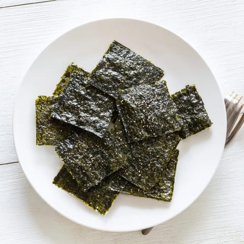 A close-up of crispy Roasted Seaweed Chips, showcasing their dark green color and crunchy, freshly roasted texture.