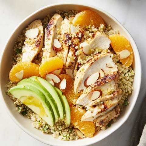 Hearty Citrus Herb Chicken Salad Bowl garnished with fresh parsley and basil, served in a white bowl beside a glass of sparkling water with lemon.