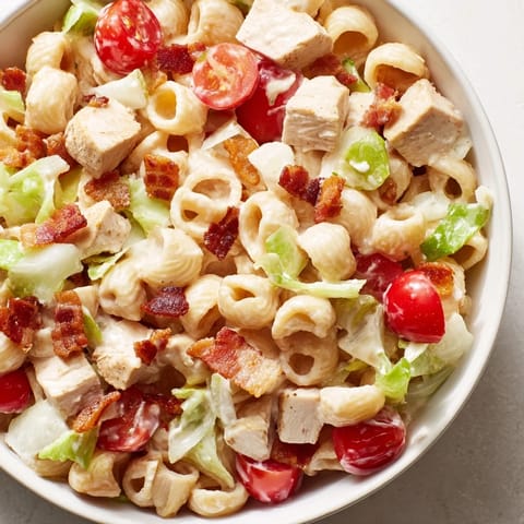 Hearty BLT Chicken Pasta Salad in a white bowl, featuring tender pasta shells, juicy tomatoes, and crumbled bacon for a picnic-ready lunch.