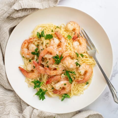 Golden, succulent shrimp nestled in silky strands of pasta, brightened by zesty lemon and aromatic garlic, perfect for a light weeknight dinner.  