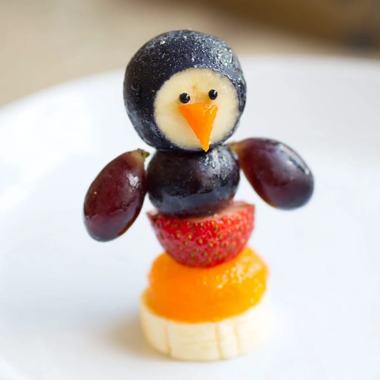 Bright, colorful Penguin Fruit Skewer Army arranged perfectly as penguins: a sweet and healthy treat.