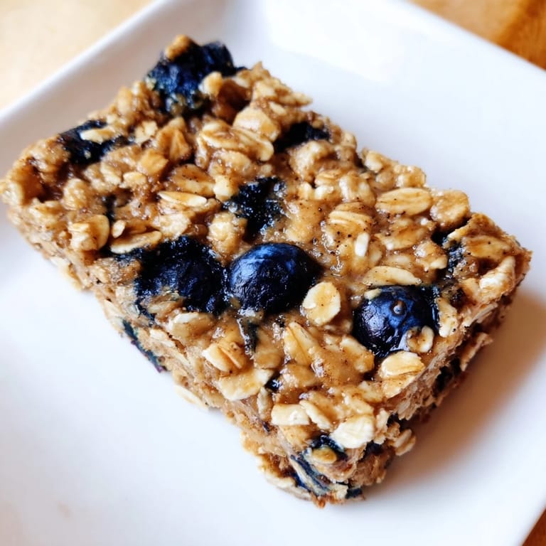 Freshly baked Blueberry Banana Oatmeal Protein Bars with visible blueberries, perfect for on-the-go snacking.