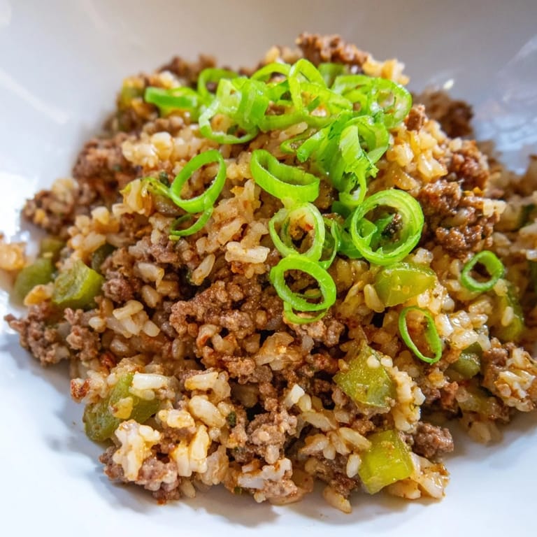 Savory close-up of Cajun Dirty Rice, a rich, hearty rice dish ready to serve garnished with green onions.