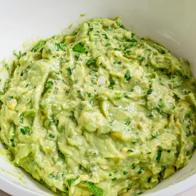 Bright green avocado lime dip garnished with cilantro, ready to serve with veggies.