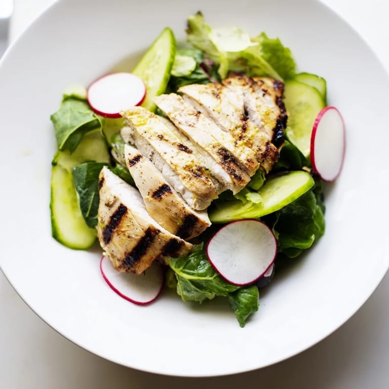 Enjoy a close-up of Spring Detox Chicken Salad with sliced cucumbers, radishes, and mixed greens tossed in a light, tangy dressing.
