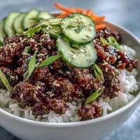 Steaming bowls of Easy Korean Beef Bowl garnished with fresh green onions, sesame seeds, and vibrant carrots.